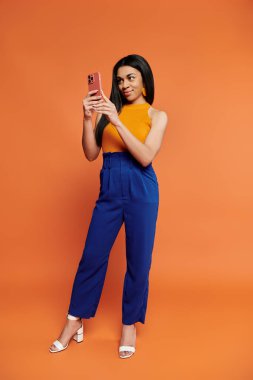 Canlı giyinmiş neşeli bir kadın akıllı telefonuyla iletişim kuruyor..