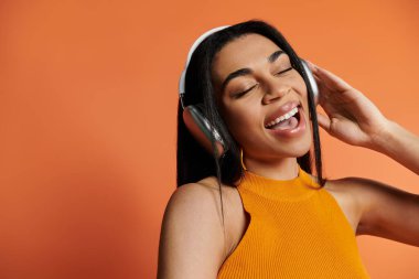 Bir kadın kulaklıkla müzik dinlerken mutlu bir şekilde gülümser..