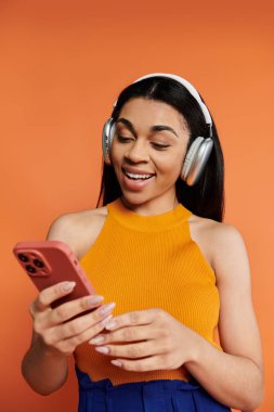 Gülümseyen kadın akıllı telefonuyla uğraşırken kulaklıkla müzik dinliyor..