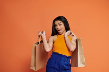 A cheerful woman showcases her shopping bags with a playful expression. clipart