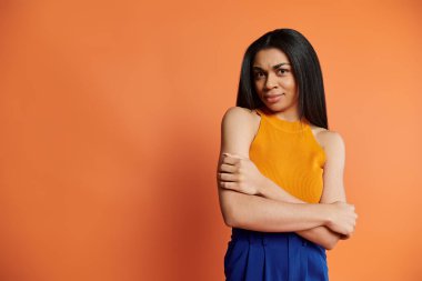 Kendine güvenen bir kadın kollarını kavuşturarak ve sıcak bir gülümsemeyle tarzını sergiler..