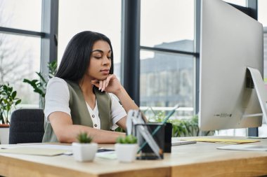 Düşünceli bir kadın modern bir ofis ortamında işiyle meşgul olur..