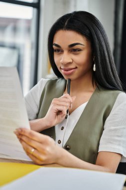 A thoughtful woman examines important documents with a pen in hand. clipart