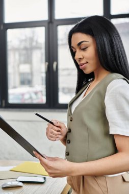 Dengeli bir kadın, iş yerinde önemli evrakları dikkatlice inceler..