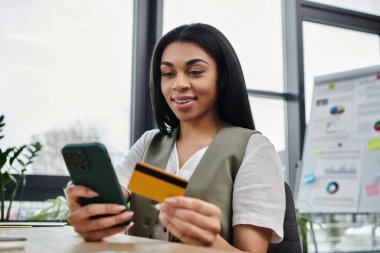 Genç bir kadın akıllı telefonunu kullanarak internetten alışveriş yapmaktan hoşlanır..