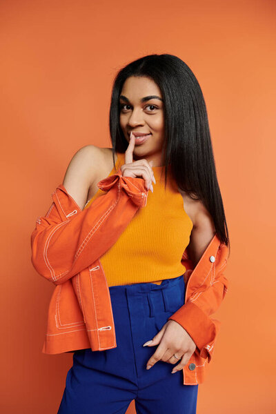 A stylish woman playfully holds a finger to her lips, inviting intrigue and charm.