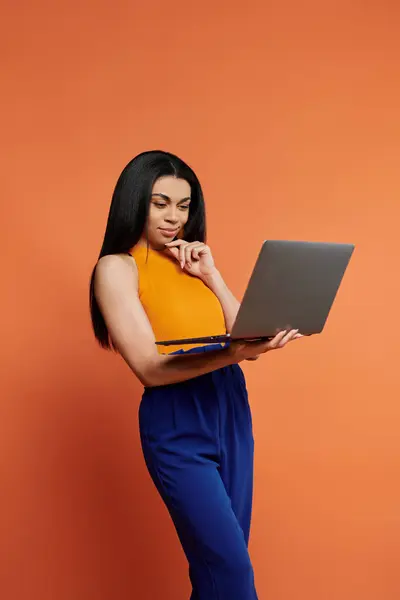 stock image A woman in a colorful outfit contemplates while using her laptop.