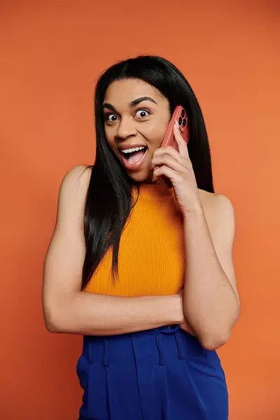 stock image A vibrant young woman animatedly chatting on her phone, radiating energy and joy.