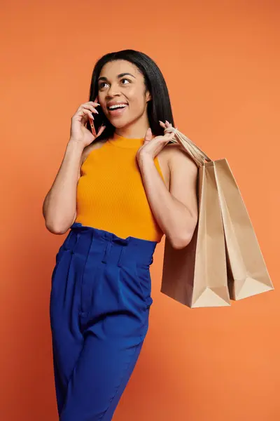 stock image A fashionable woman enjoys a call while holding shopping bags.