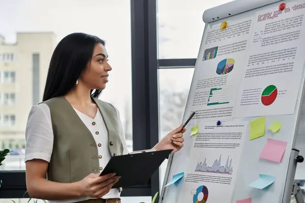 stock image A confident woman presents data insights in a bright workspace.