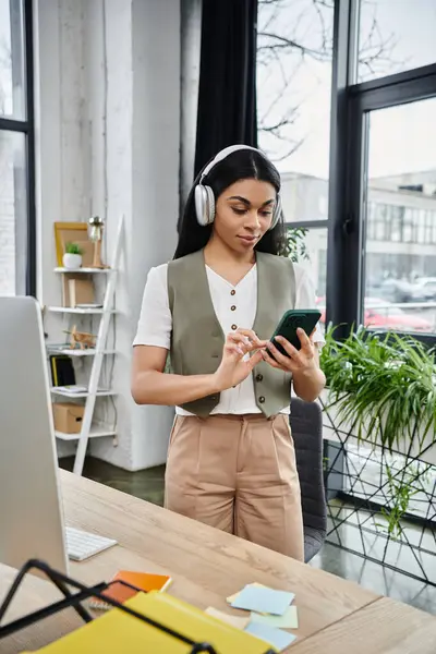 stock image Young woman interacts with her smartphone while wearing headphones.