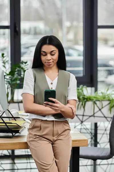 stock image Confident woman interacts with her smartphone while leaning on a stylish desk.