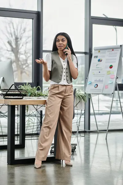 stock image A poised woman discusses business matters while standing in a bright office.