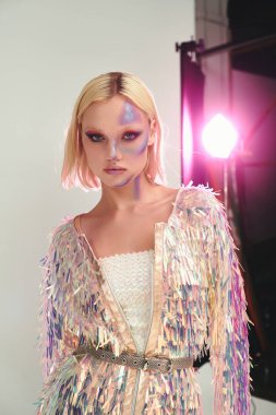 Şık bir genç kadın, canlı bir atmosferde holografik moda sergiliyor..