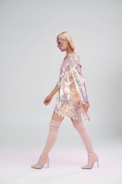 Şık bir kadın kendine güvenerek yürür, ışıldayan holografik bir moda sergiler..