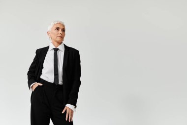 Kendine güvenen olgun bir kadın şık elbisesini zarif bir duruşla sergiliyor..