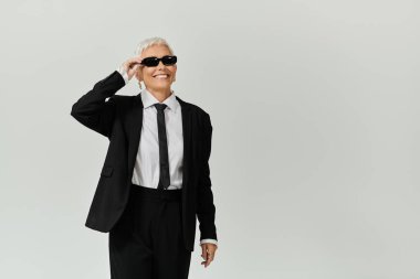 Kendine güvenen akıllı bir kadın neşe içinde güneş gözlüğü takıyor..