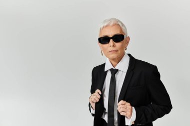 Kendine güvenen bir kadın şık bir kıyafet ve güneş gözlüğü ile moda anlayışını sergiliyor..