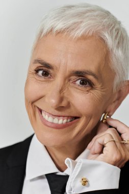 Kendine güvenen bir kadın zarif küpelerini düzeltirken sıcak bir şekilde gülümser..