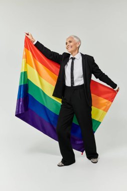 Embracing pride and joy while holding a vibrant rainbow flag. clipart