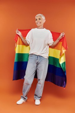 A confident woman joyfully showcases her pride wearing a rainbow flag. clipart