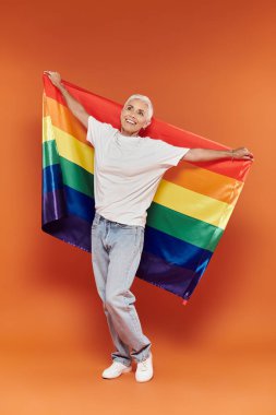 Şık bir kadın neşe içinde elinde gökkuşağı bayrağı, gurur ve güven saçıyor..