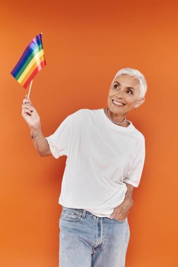 A stylish woman joyfully waves a rainbow flag, celebrating love and acceptance. clipart