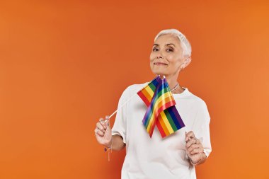 A stylish woman proudly holds a rainbow flag, exuding confidence and joy. clipart