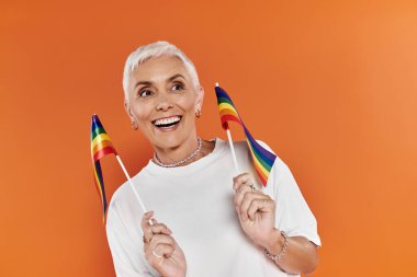 Neşeli bir kadın gururla gökkuşağı bayrakları sallar, kendine güven ve gurur yayar..