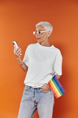 A mature woman confidently checks her phone while showcasing her fashion. clipart