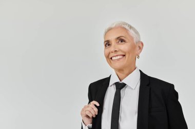 Şık giyinmiş kendinden emin kadın çağdaş bir arka planda neşe saçıyor..
