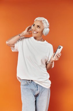Neşeli bir kadın telefonunu tutarken müzik dinler..