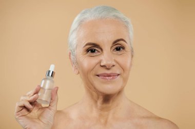 Kısa saçlı, elinde serum şişesi olan olgun bir kadın..