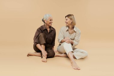 Two generations share smiles and laughter in a cozy, warm toned space. clipart