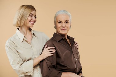 Bir anne ve kızı, gülümsemeyle kucaklaşarak, samimi bir anı paylaşırlar..