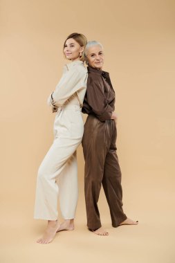 İki kadın aynı anı paylaşıyor. Sırt sırta verip eşgüdümlü kıyafetler giyiyorlar..