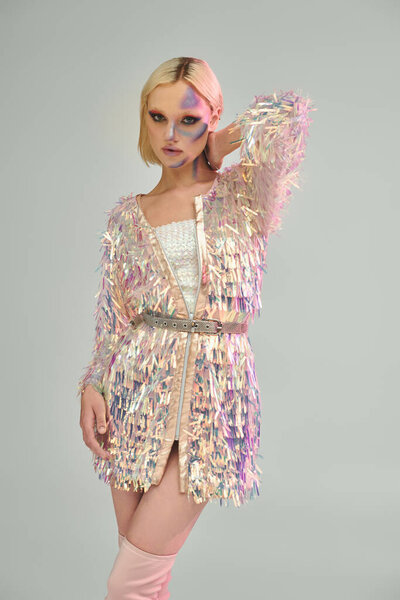 Потрясающая молодая женщина уверенно позирует в модном наряде с голографическими деталями.