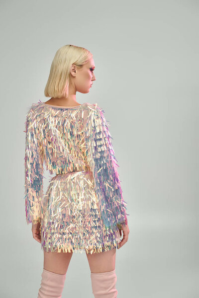 Стильная молодая женщина уверенно демонстрирует свой блестящий наряд.