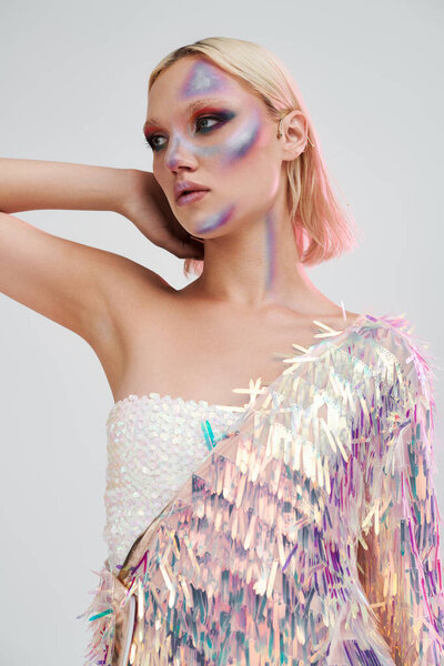 Модная молодая женщина очаровывает своей голографической одеждой и потрясающим макияжем.