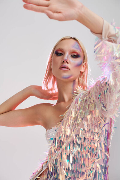 Молодая женщина выставляет напоказ яркий голографический наряд в выразительной позе.