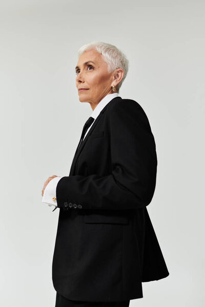 A mature woman with short hair exudes confidence in fashionable attire.