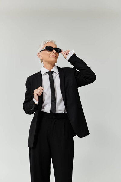 Зрелая женщина демонстрирует свой стильный вид и уверенное поведение с шикарной позой.