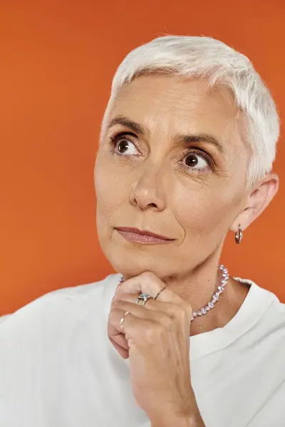 stock image A mature woman ponders thoughtfully while dressed in chic attire.