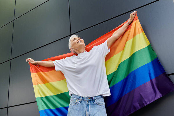 A vibrant moment of pride as a woman joyfully displays a rainbow flag.