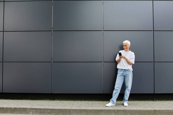 Модная взрослая женщина с телефоном в изящной городской обстановке.