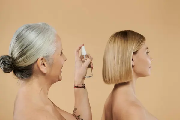 stock image Mother applies hair product to daughter, showcasing beauty and connection.