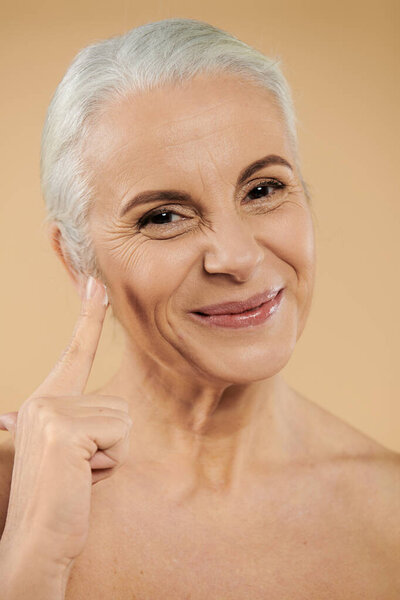 A woman smiles sweetly while using face cream.