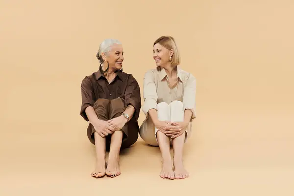 stock image Two women share smiles and laughter while sitting on a soft surface.