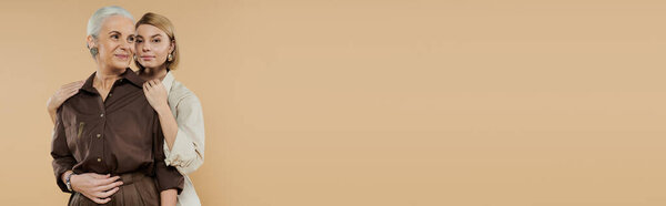 Взрослая женщина и ее взрослая дочь разделяют сердечные объятия.