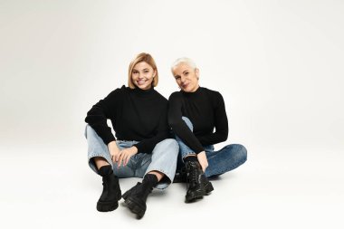 Bir anne ve kızı, şık kıyafetlerini sergileyerek neşeli bir anı paylaşıyor..